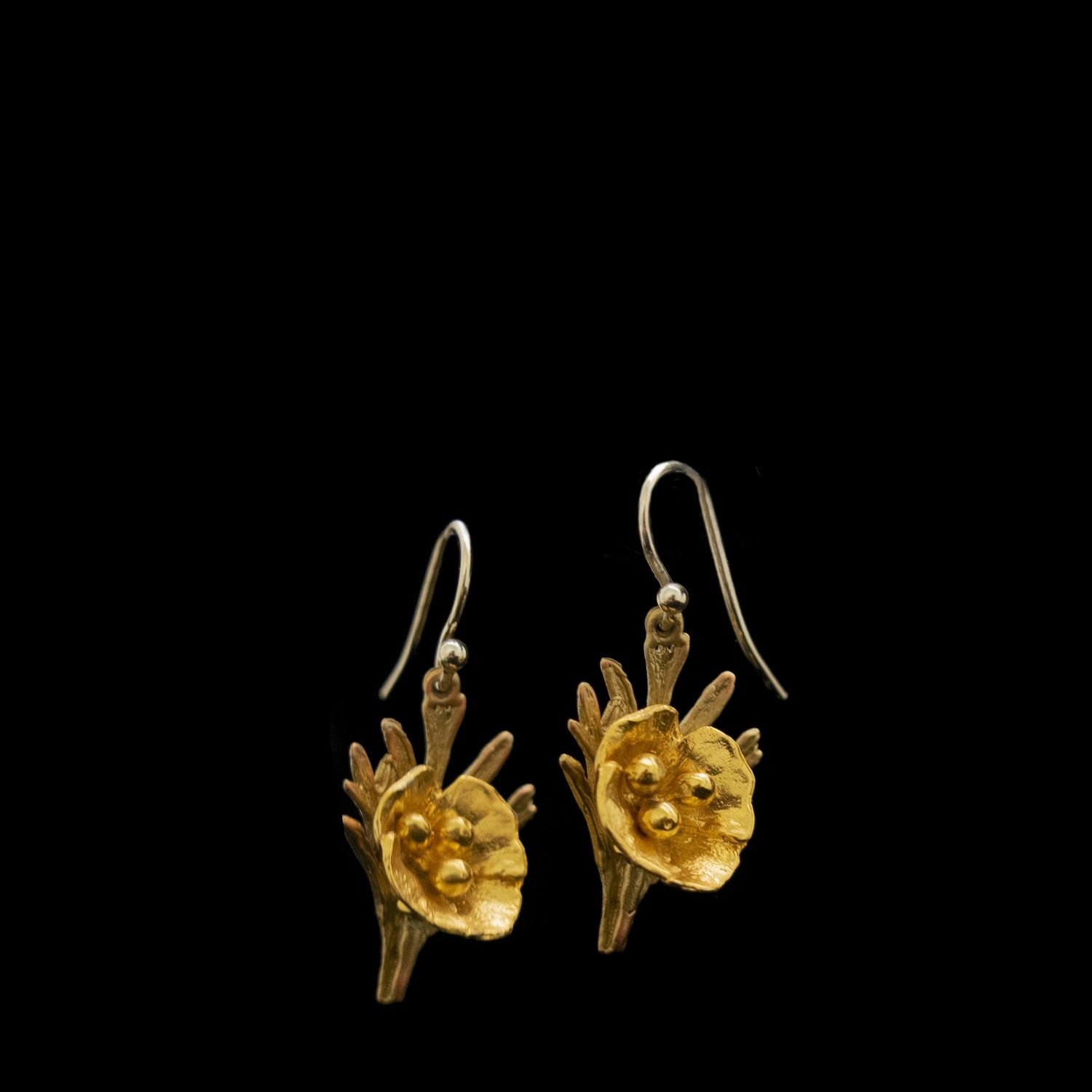 A pair of gold earrings with floral designs and intricate detailing, displayed against a black background.