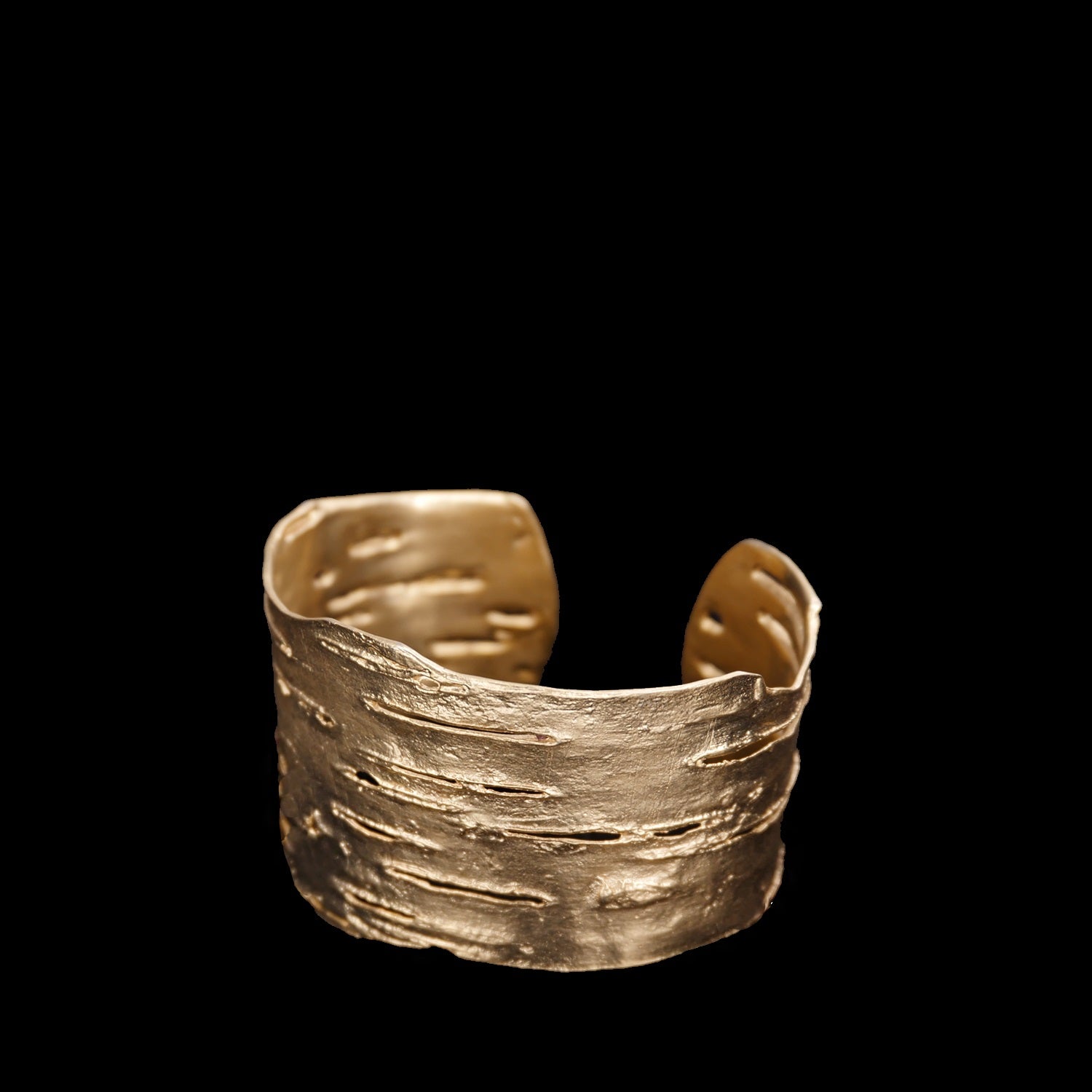 Wide gold cuff bracelet with a textured, bark-like surface, displayed on a black background.