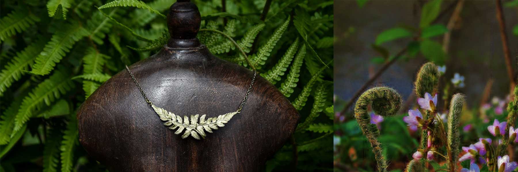 A gold fern leaf necklace displayed on a dark wooden bust, with green ferns in the background; purple wildflowers and curled ferns are visible to the right.
