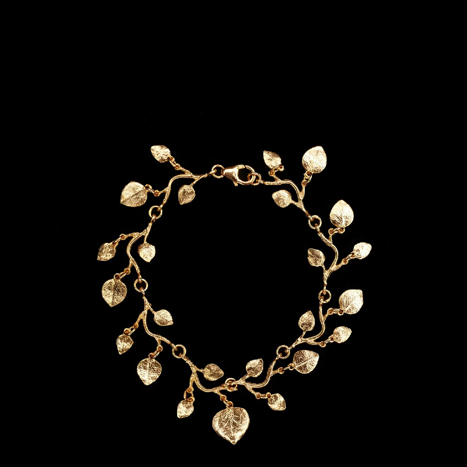 Gold bracelet designed with multiple small, detailed leaf charms linked together, displayed against a black background.