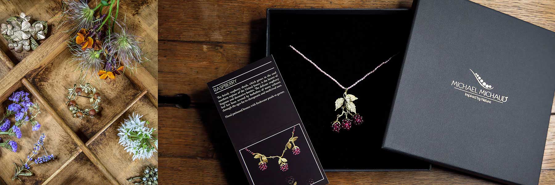 Assorted botanical jewelry and loose flowers on a wooden tray, with a berry-themed necklace displayed in a black Michael Michaud box and accompanying information card on a wooden surface.