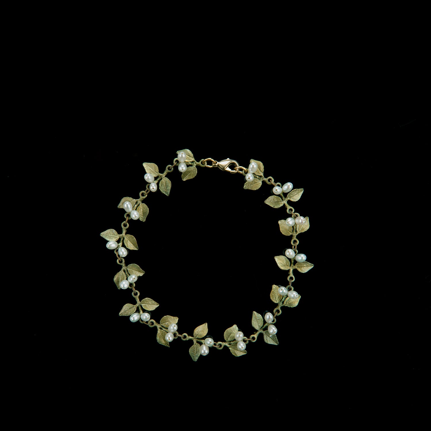 Gold bracelet featuring alternating small green leaves and white pearls, arranged in a circular pattern, displayed on a black background.
