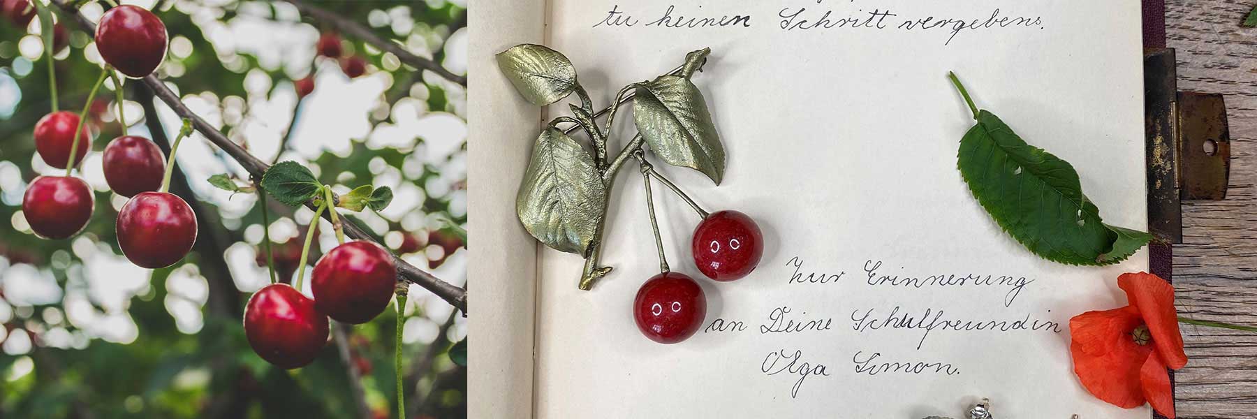 A branch of red cherries on the left and an open notebook on the right with handwritten German text, a silver leaf, artificial cherries, and an orange flower on the page.