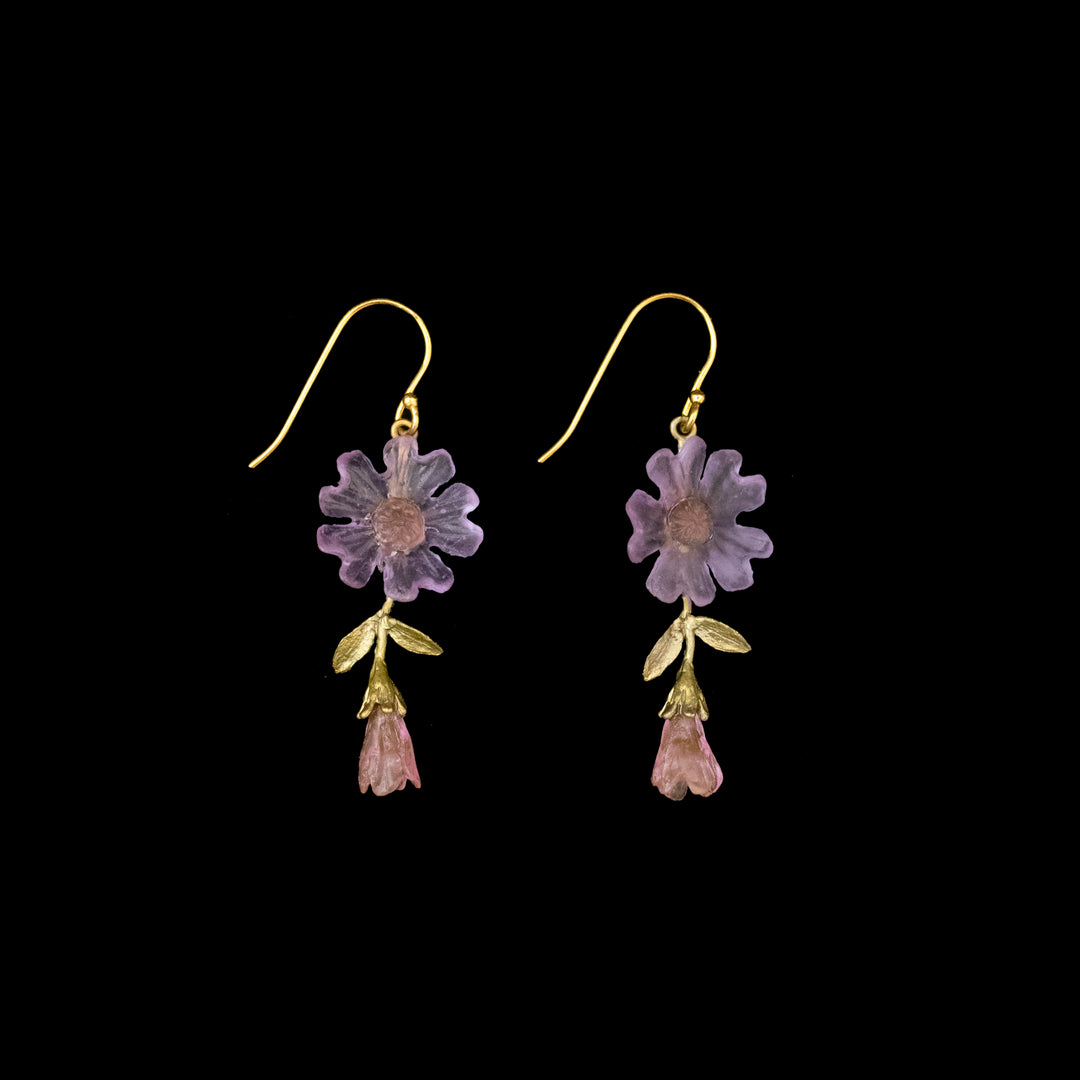 A pair of gold hook earrings featuring purple flower-shaped and pink bud-shaped elements with gold leaves, set against a black background.