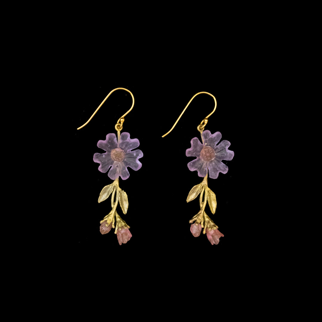 A pair of gold hook earrings with purple flower-shaped pendants and small pink and gold leaf-shaped charms hanging below.