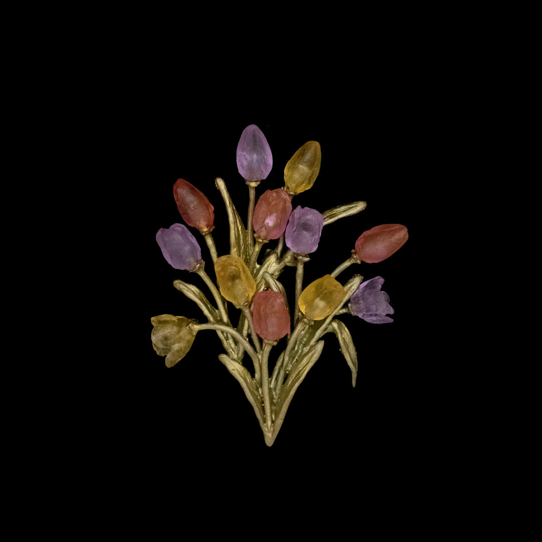 A green-tone tulip brooch shaped like a bouquet, featuring cast glass flowers in purple, yellow, and red buds set against a striking black background.