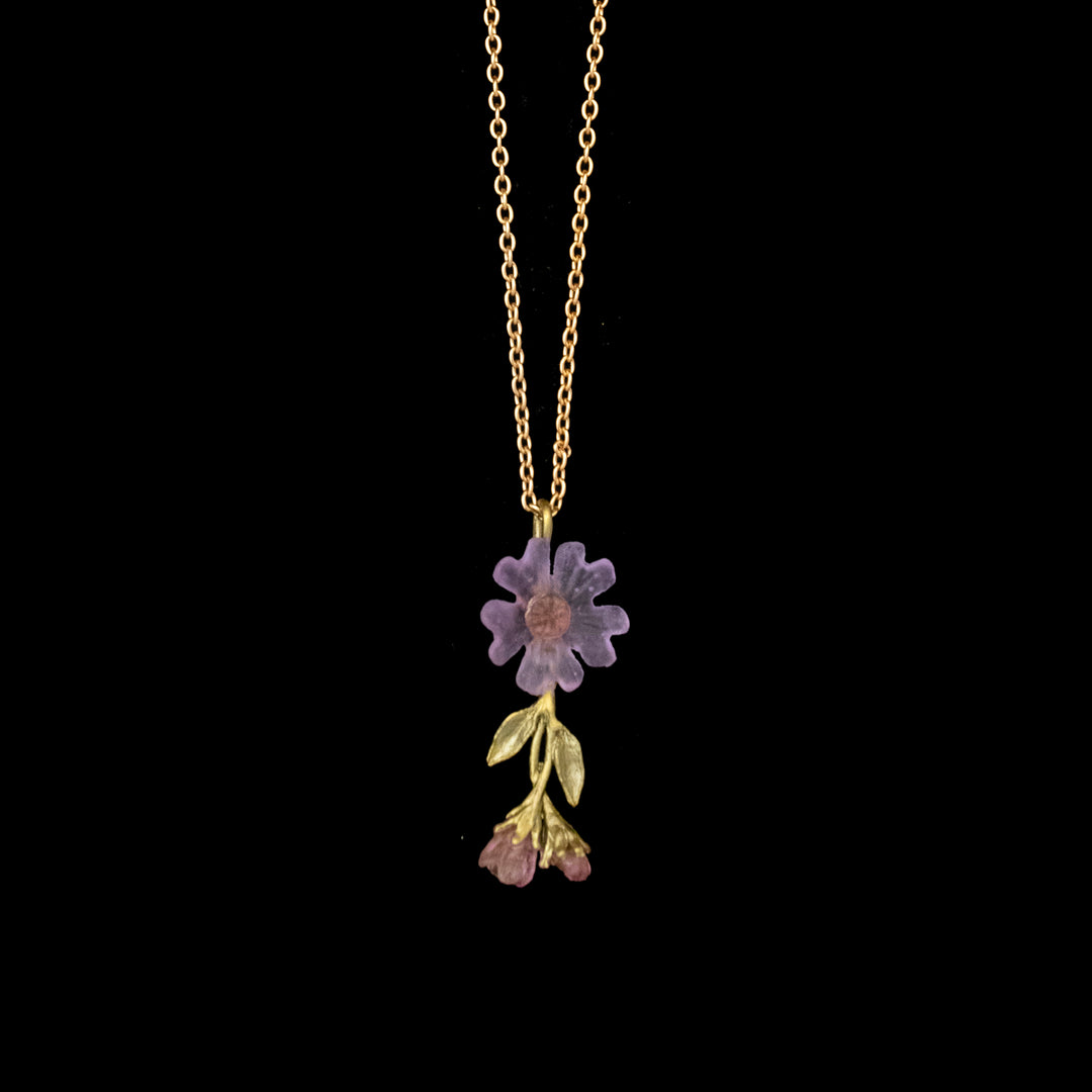 Gold chain necklace with a pendant featuring a large purple flower, two green leaves, and two small purple flower buds, displayed on a black background.