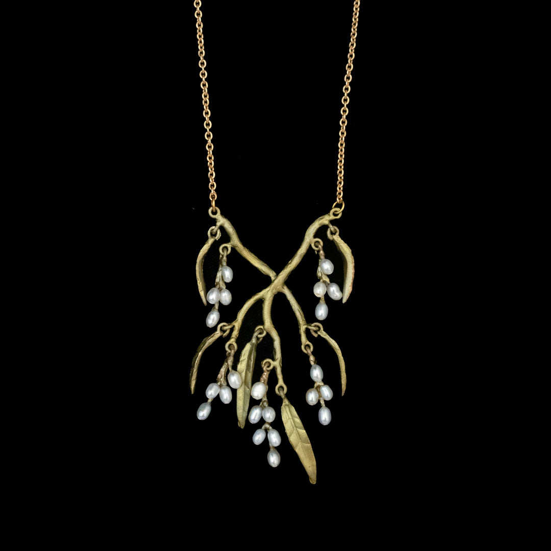The Weeping Willow Necklace features a green branch-shaped pendant with leaves and clusters of small white pearls, displayed on a black background.