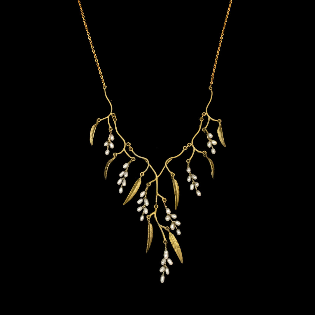 The Weeping Willow Necklace - Statement features a gold, branch-inspired design with fine leaves and clusters of white pearls, capturing the beauty of nature against a striking black background.