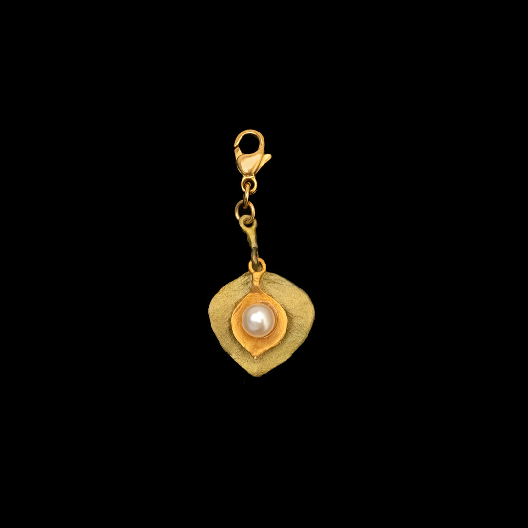 A nature-inspired charm featuring two hand-shaped leaves, one patinated in bronze and the other in 24kt gold plating, with a freshwater pearl at the center.