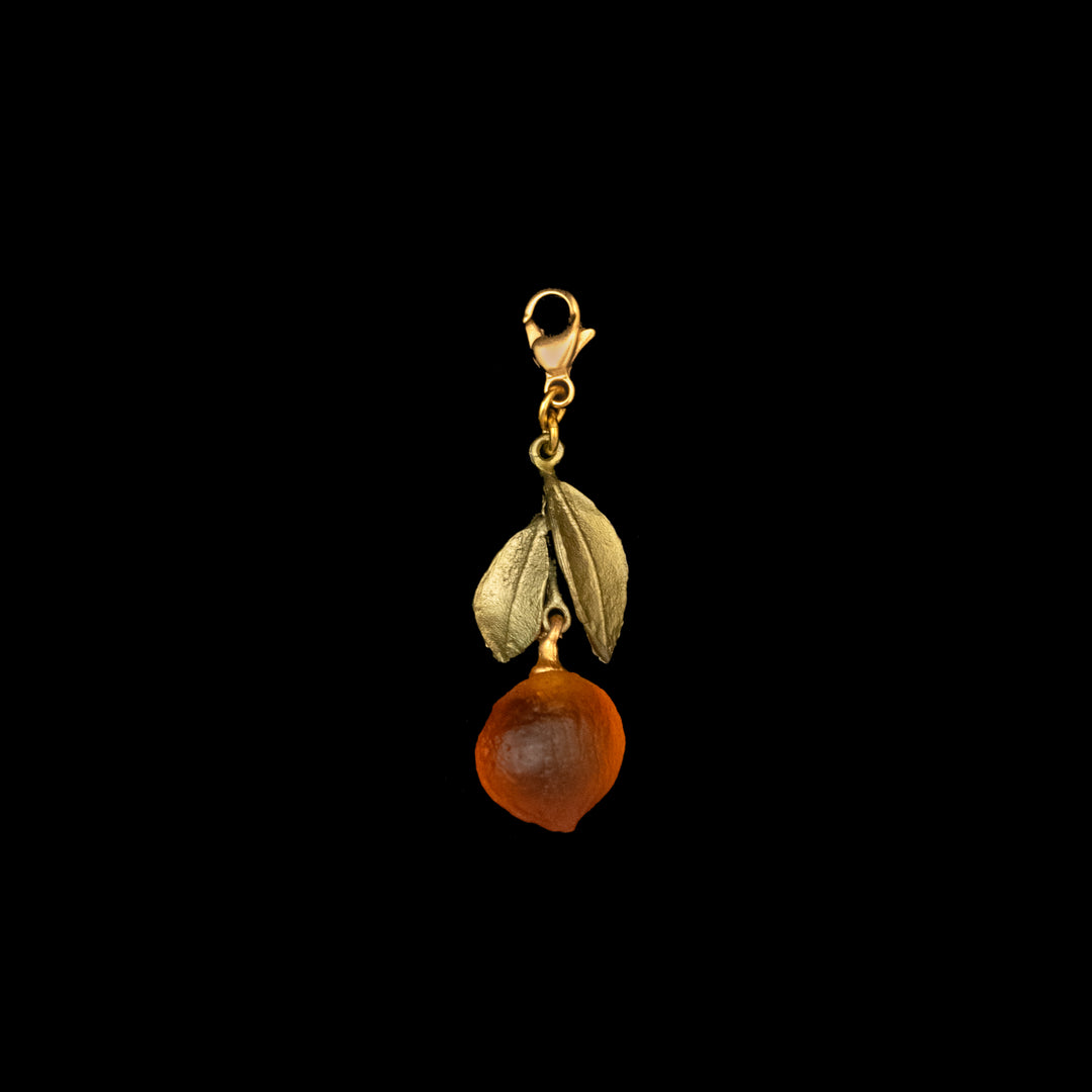green pendant featuring a textured leaf and an orange charm, suspended from a lobster clasp, on a black background—a unique piece of citrus jewelry.