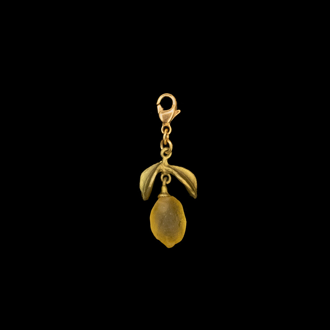 A green-toned Lemon Charm with a clasp, featuring a yellow citrus jewelry pendant and hand patinated bronze leaf accents against a black background.