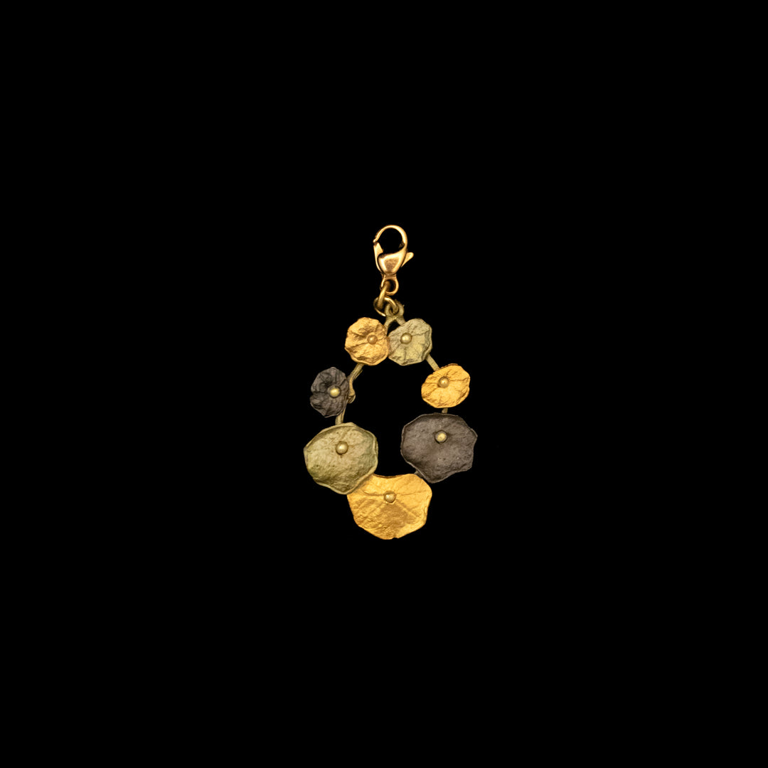 A gold, grey and green charm featuring overlapping, textured Nasturtium leaves in a circular pattern with a lobster clasp at the top, set against a black background.
