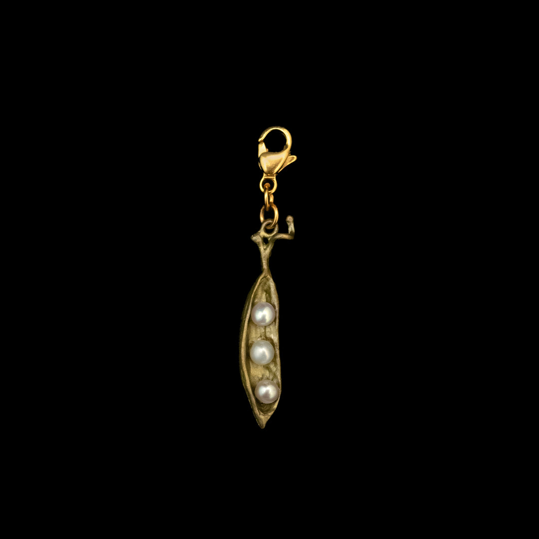A Pea Pod Charm crafted in green bronze, featuring three freshwater pearls nestled inside a bronze pod and secured with a lobster clasp, set against a black background.