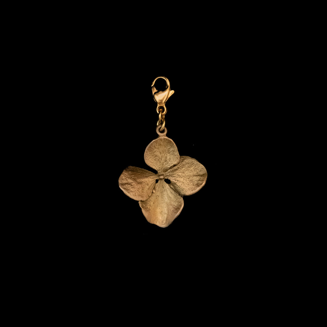 A gold-colored metal hydrangea charm pendant in the shape of a four-petal flower with a lobster clasp, displayed on a black background.