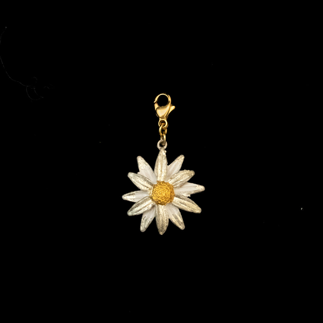 A Daisy Charm featuring a white and yellow daisy flower with a gold lobster clasp is displayed against a black background, perfect for adding a touch of bronze jewelry elegance to any accessory.