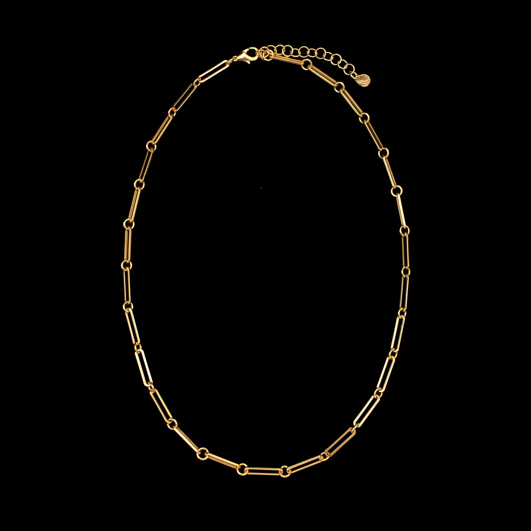 A gold-colored charm necklace with a geometric pattern, displayed against a black background.
