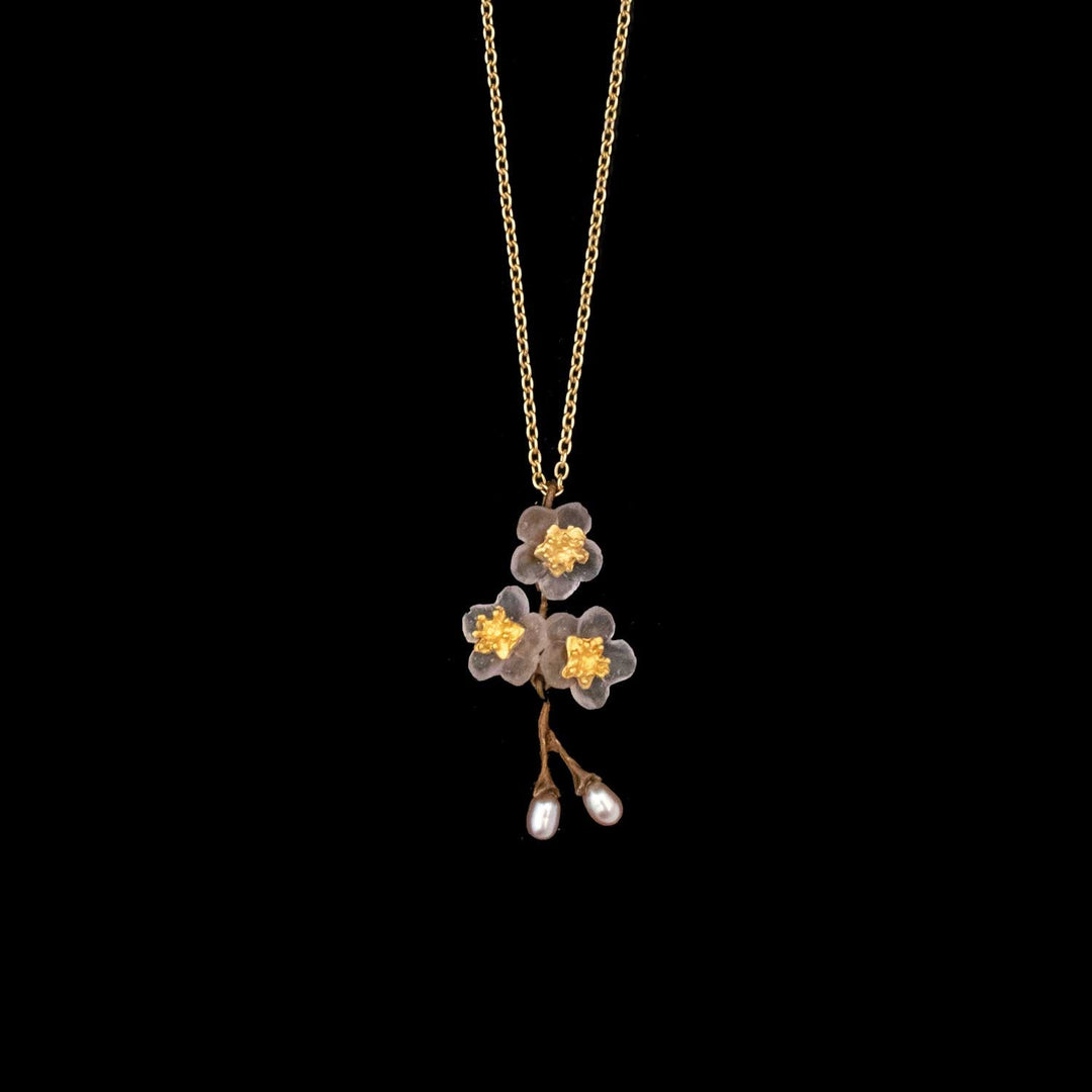 Golden chain necklace featuring a pendant with three gold and white floral-inspired blossoms and two hanging pearl buds, displayed on a black background. Perfect for lovers of cherry blossom jewelry.