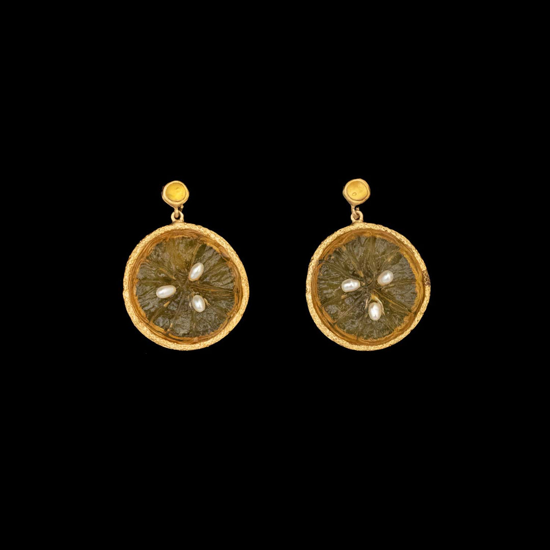 A pair of round, gold-plated bronze earrings with textured orange glass centers and three small pearl accents inside each earring, showcased on a black background—a unique touch of botanical jewelry.