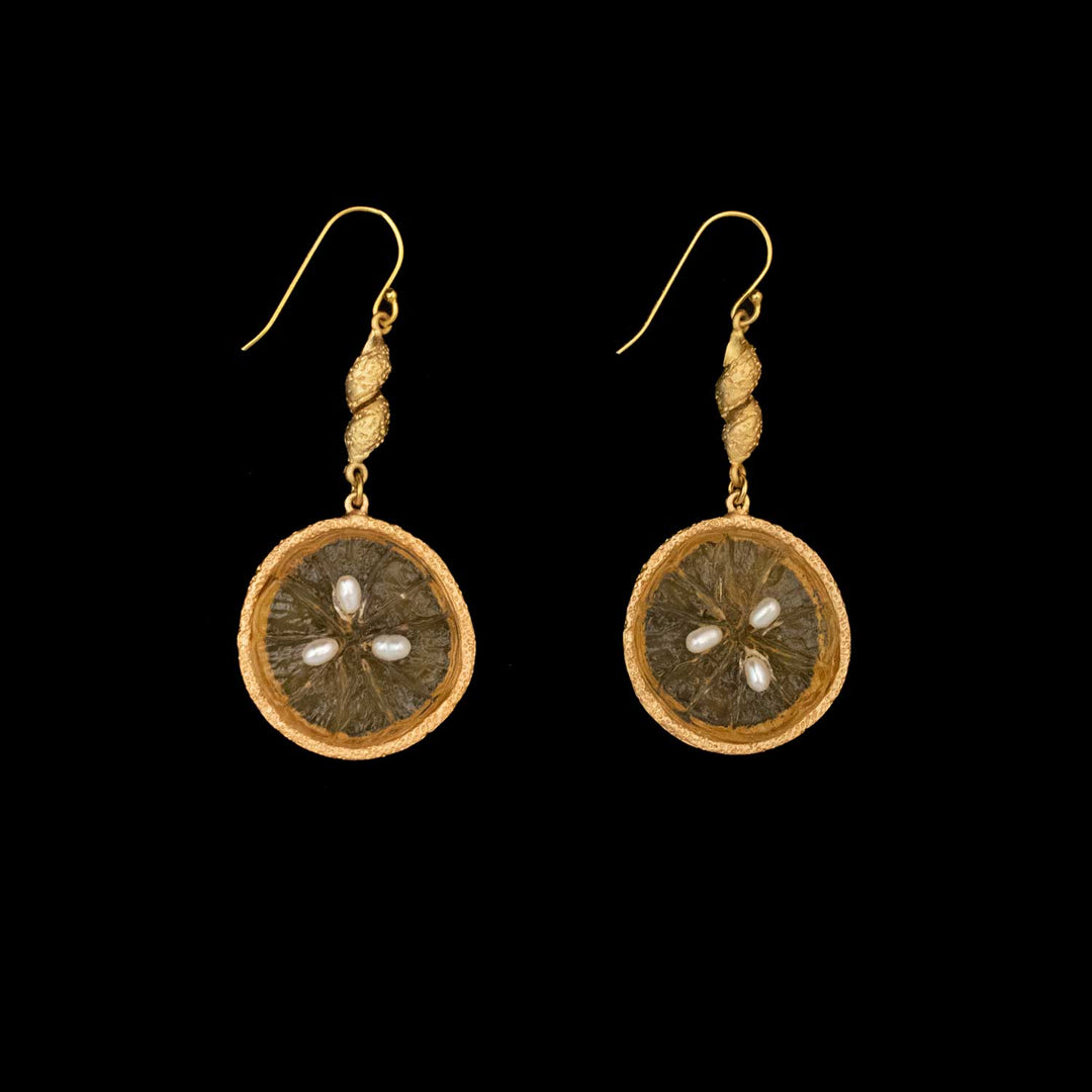 A pair of Michael Michaud Jewelry Orange Earrings, crafted from 24kt gold plated bronze, features circular dried fruit slices with embedded pearl details, beautifully displayed on a black background.