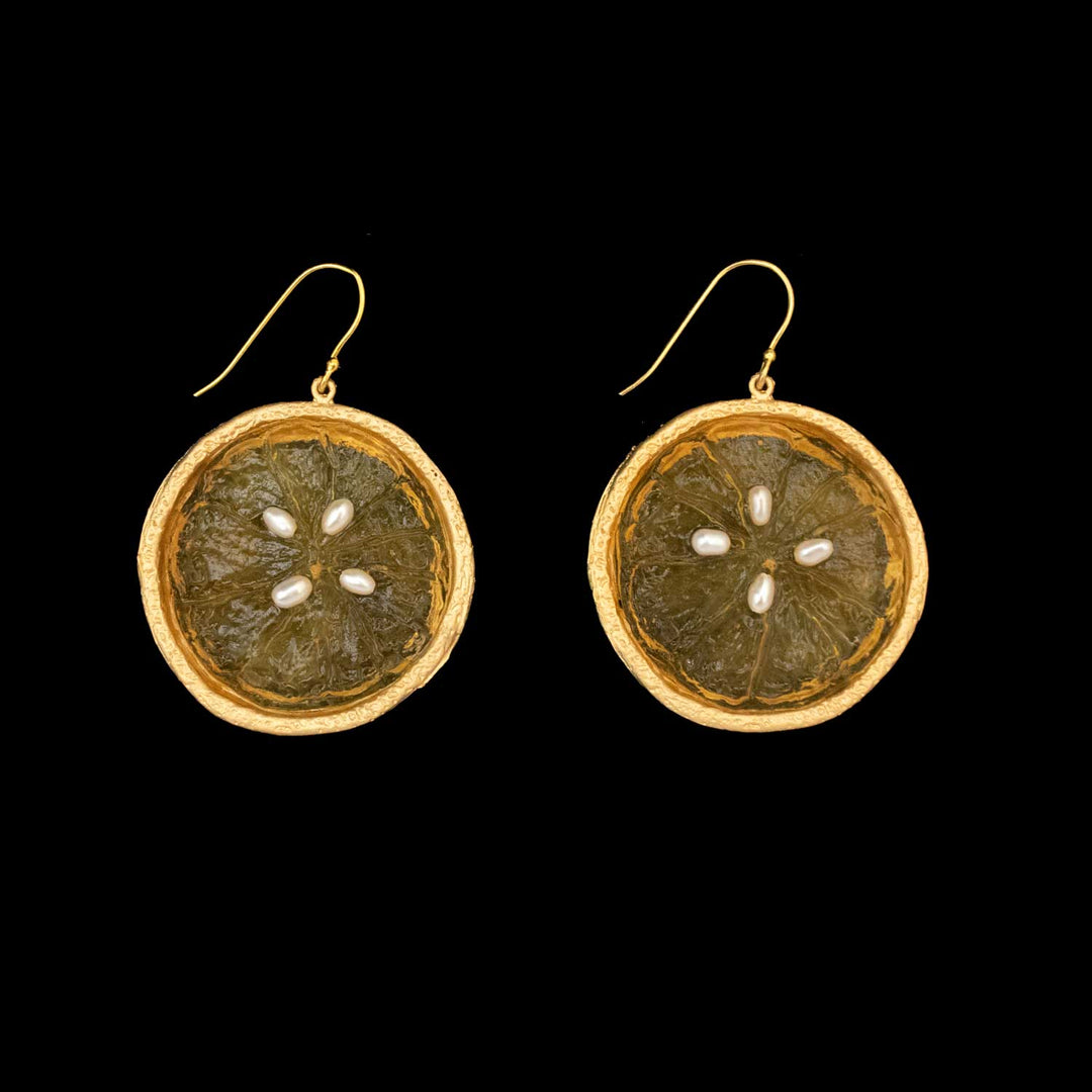 Citrus Earrings - Large Wire Orange: round, fruit slice-inspired earrings with gold-plated edges, translucent orange centers, and white seed accents, displayed on a solid black background.