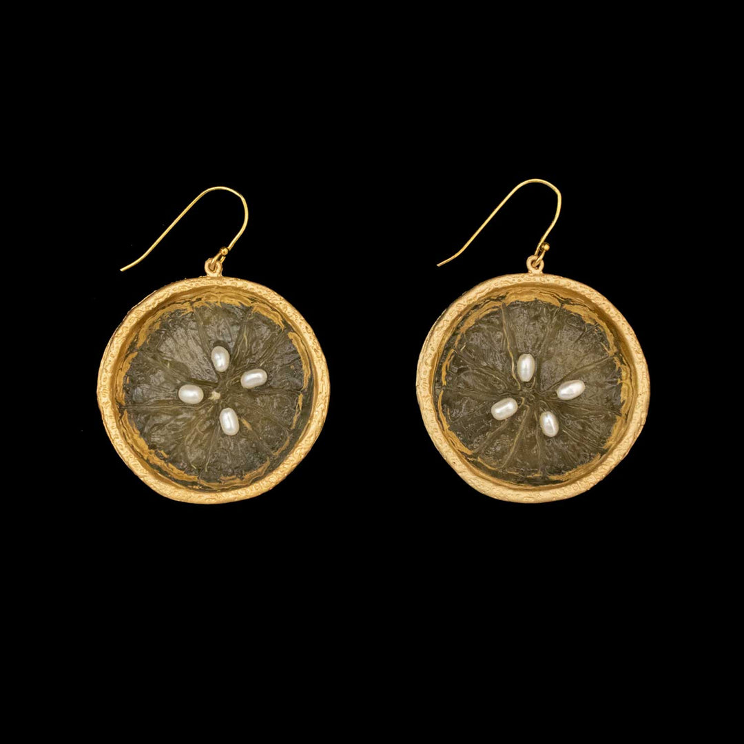 The Citrus Earrings - Large Wire Lemon feature circular lemon slices with translucent yellow centers, four white oval pearls in a star pattern, and gold plated silver hooks. Inspired by Michael Michaud Jewelry. Shown on a black background.
