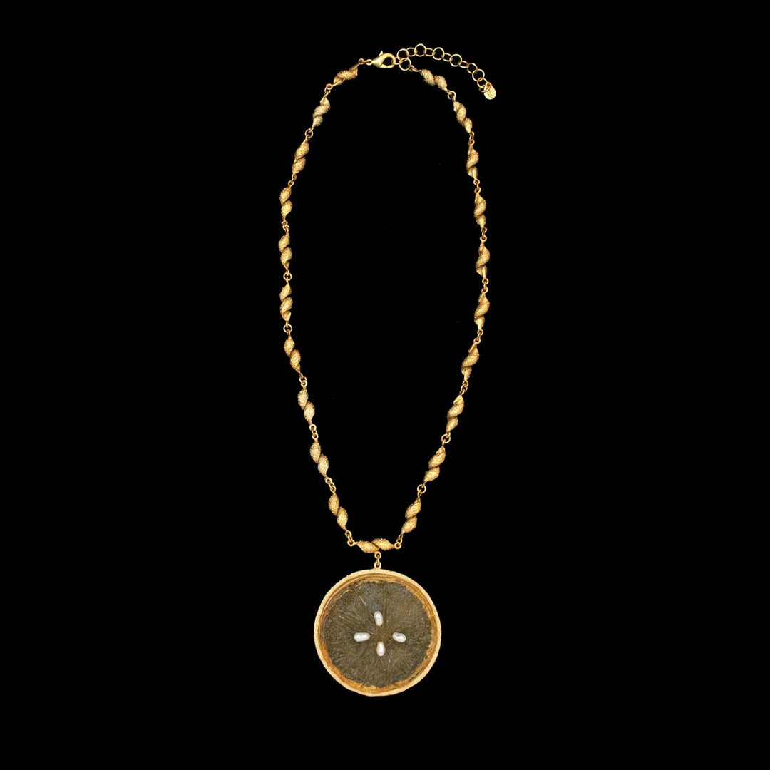 The Citrus Orange Necklace features twisted gold links and an adjustable clasp, highlighted by a bold round pendant in the center—an elegant piece reminiscent of Michael Michaud Jewelry, shown on a striking black background.