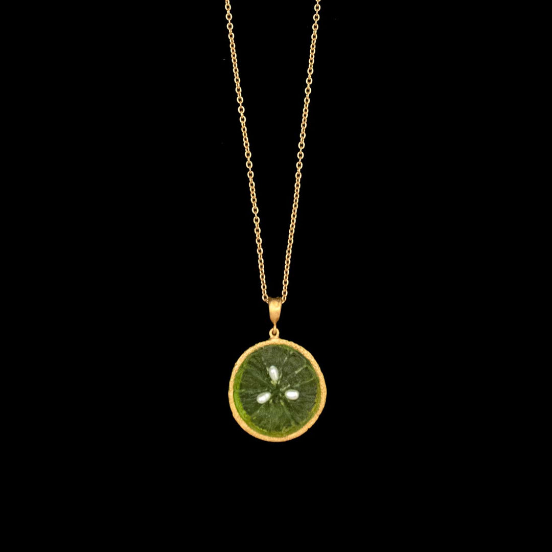 The Citrus Pendant - Lime is a 24kt gold plated necklace featuring a green citrus slice pendant with visible seeds and a gold outline, displayed on a solid black background. Inspired by Michael Michaud Jewelry.
