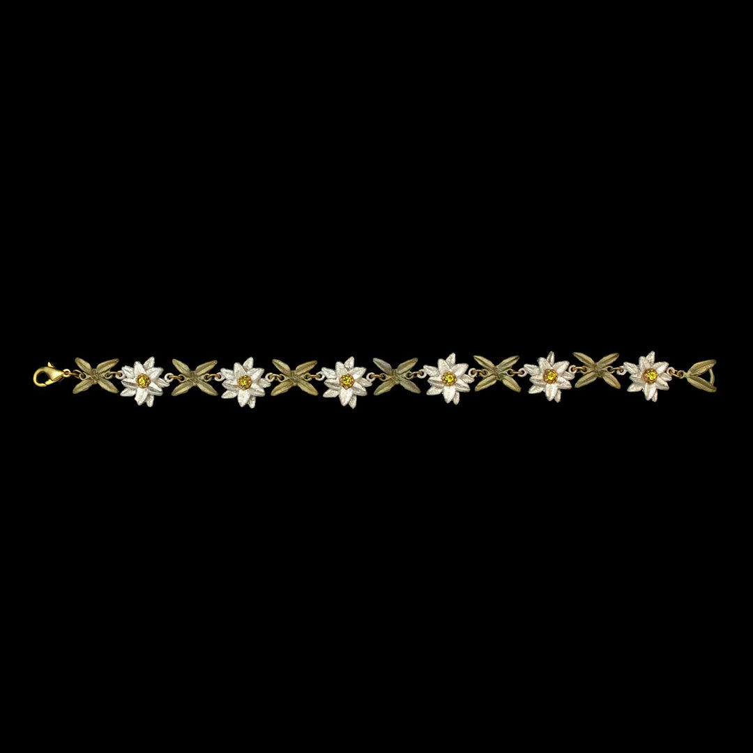 Edelweiss bracelet with a repeating pattern of white flower-leaf links, each featuring a small Austrian crystal at the center, set against a black background.