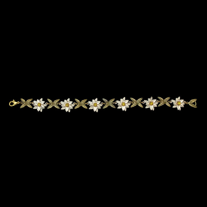 Edelweiss bracelet with a repeating pattern of white flower-leaf links, each featuring a small Austrian crystal at the center, set against a black background.