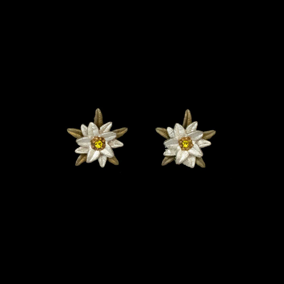 A pair of flower-shaped Edelweiss earrings with white petals, gold centers, and brown accents, reminiscent of The Sound of Music, displayed on a black background.