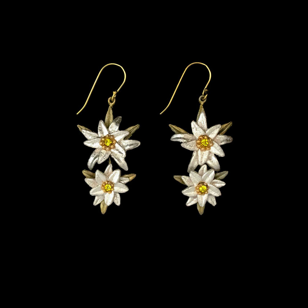 A pair of dangle Edelweiss earrings featuring two white and yellow flower-shaped charms on each earring, inspired by The Sound of Music jewelry and displayed on a black background.
