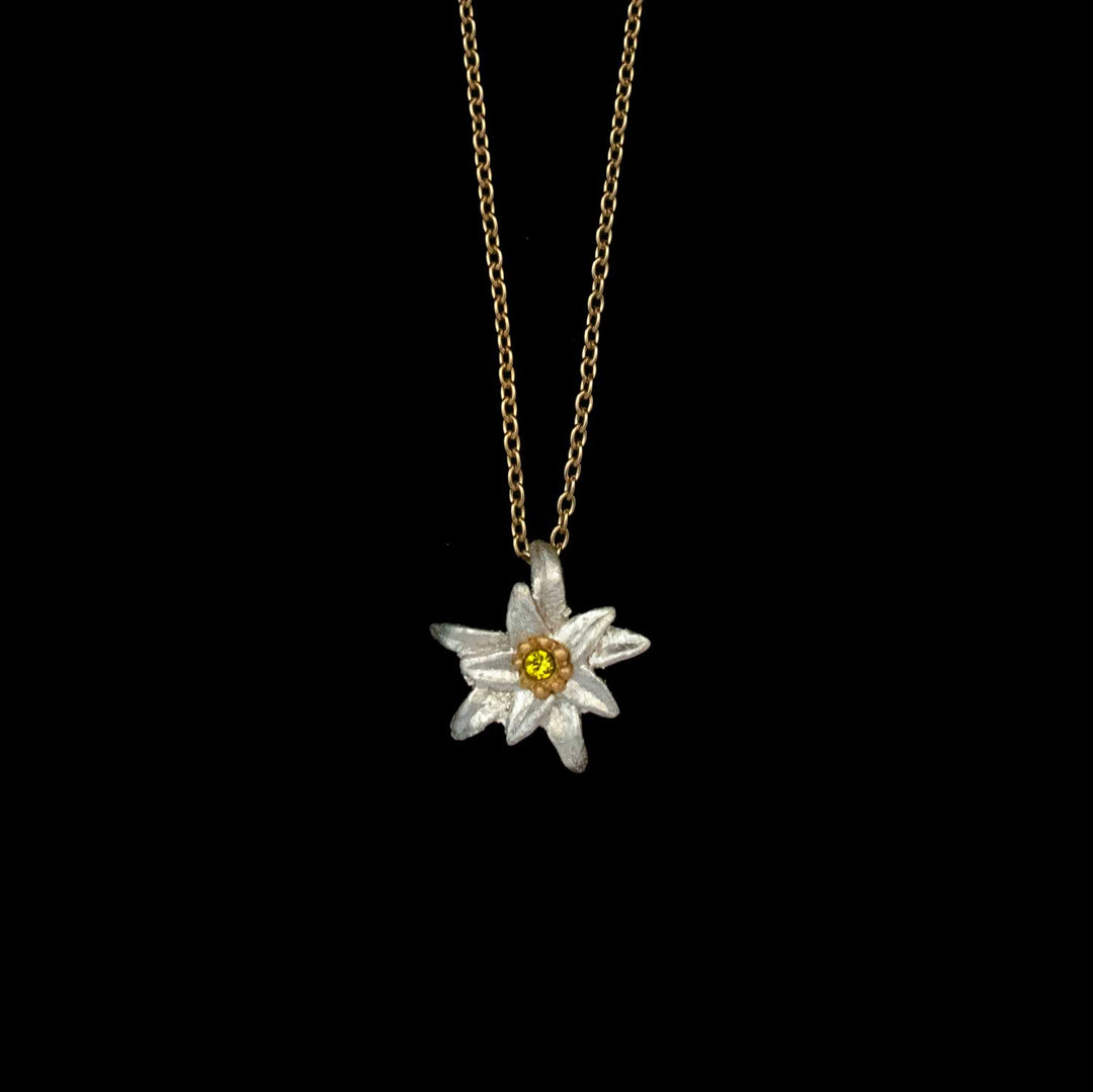 Golden chain necklace with a white Edelweiss pendant, inspired by The Sound of Music, featuring a yellow crystal center and displayed on a black background.