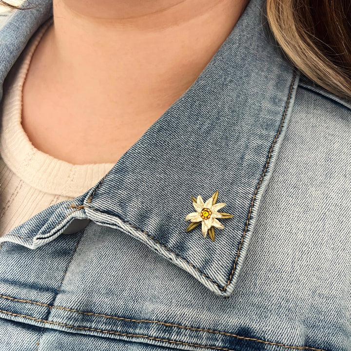 Close-up of a denim jacket with a floral brooch