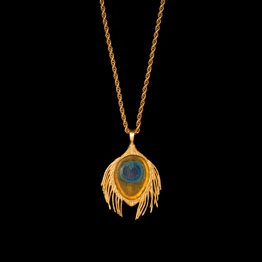 A large bronze pendant with a gold finish and blue glass accents, attached to a gold-finished chain.