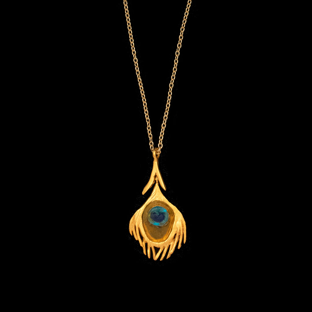 A gold-finished bronze peacock pendant with a blue and green glass center, attached to a gold-finished chain.