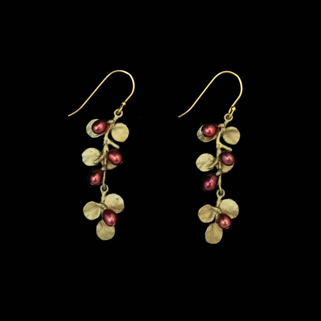 A pair of Firethorn earrings featuring gold wire hooks with leaf shapes and clusters of small, round red freshwater pearls on a black background.