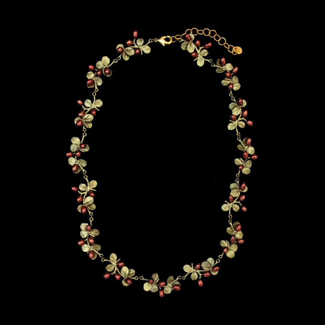 The Firethorn Necklace - Statement features small green leaves and red freshwater pearls, all displayed on a black background.