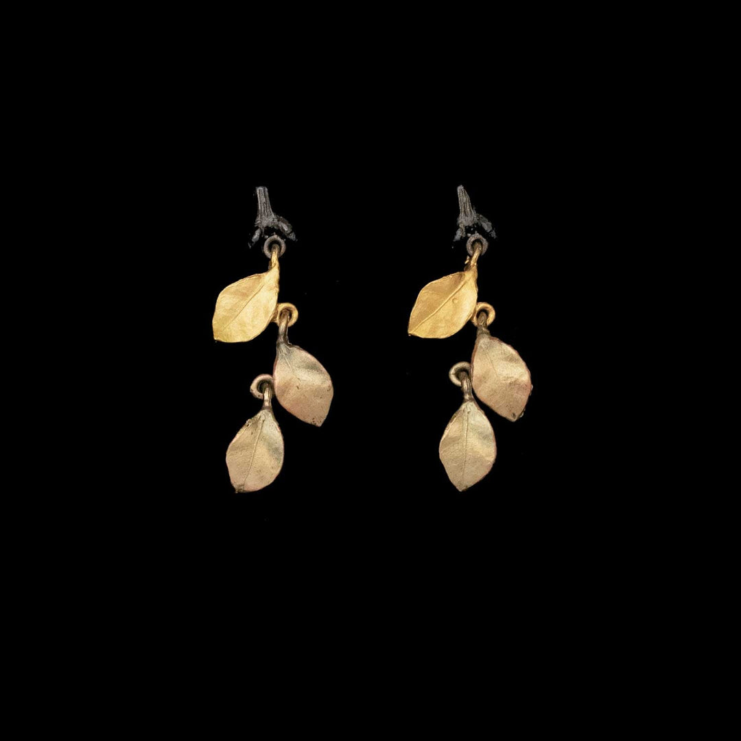 The Golden Autumn Earrings - Post feature three gold and antique bronze-toned leaves on each earring, hanging from small brown branches, displayed against a solid black background.