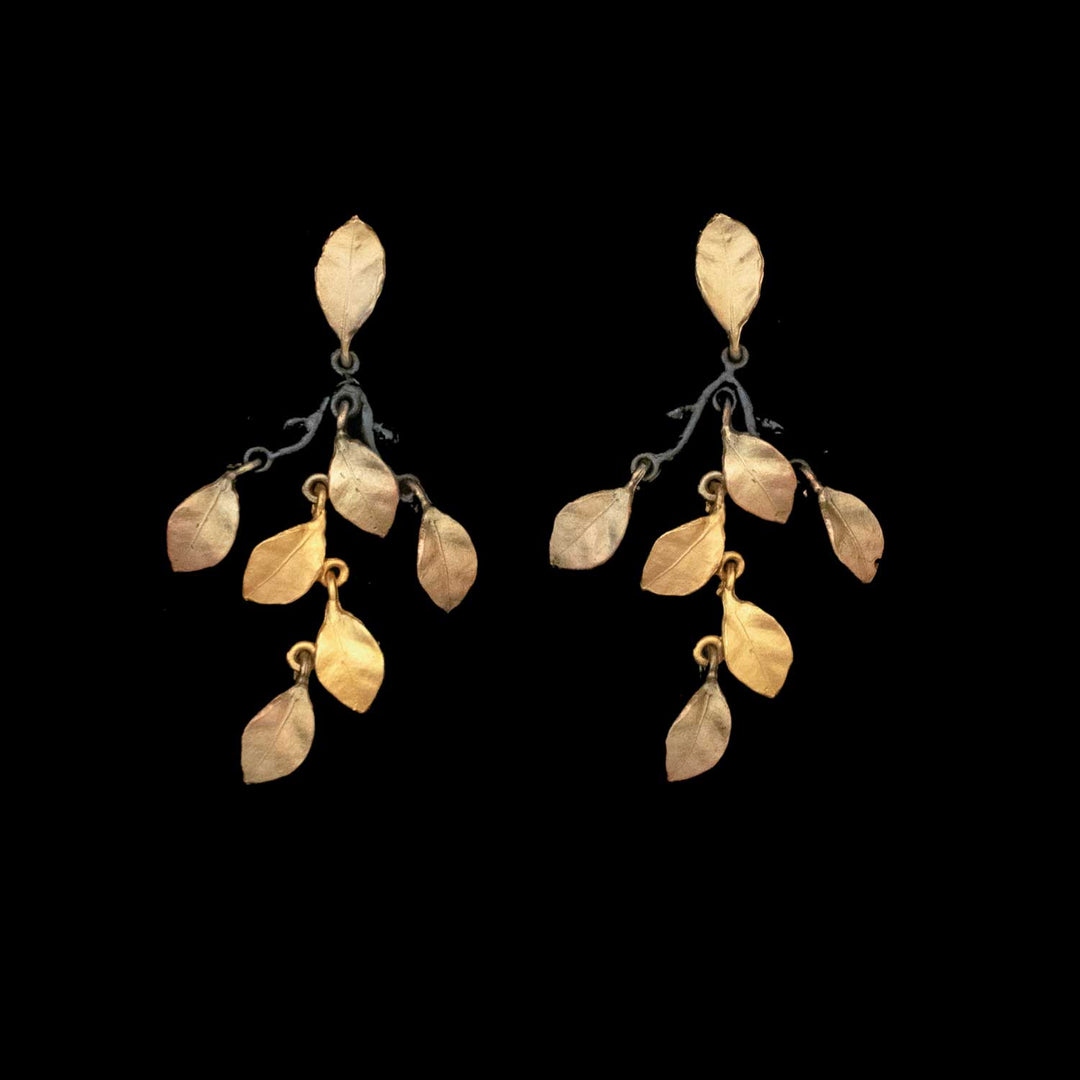The Golden Autumn Earrings - Statement Post feature gold leaf-shaped charms hanging from dark metal branches, shown against a solid black background.
