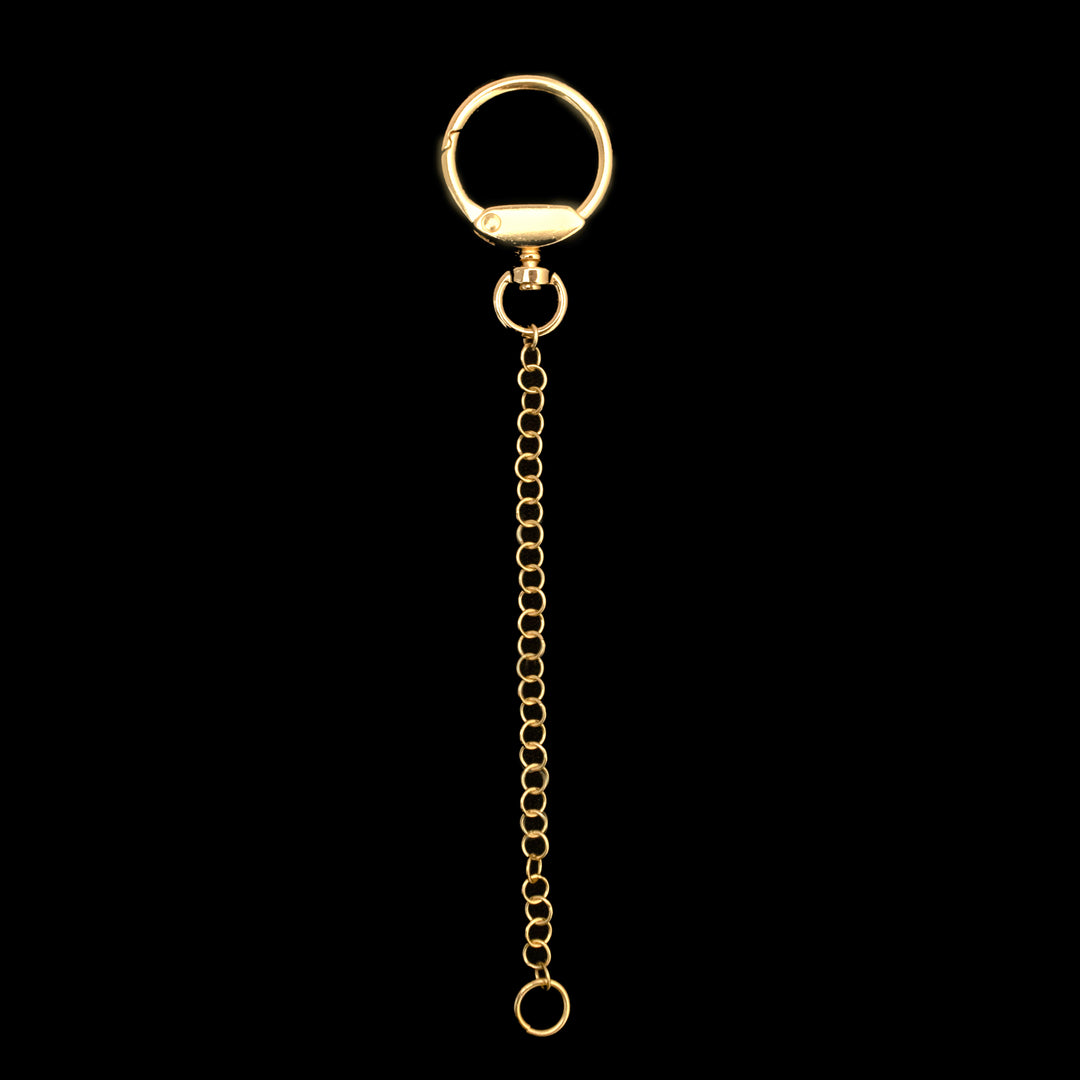 A gold keychain with a circular clasp at the top, a chain of interconnected links, and a small ring at the bottom, all set against a black background.