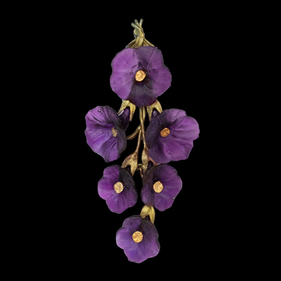 A brooch with a cluster of six purple petunia flowers with yellow centers and green stems arranged vertically against a black background.