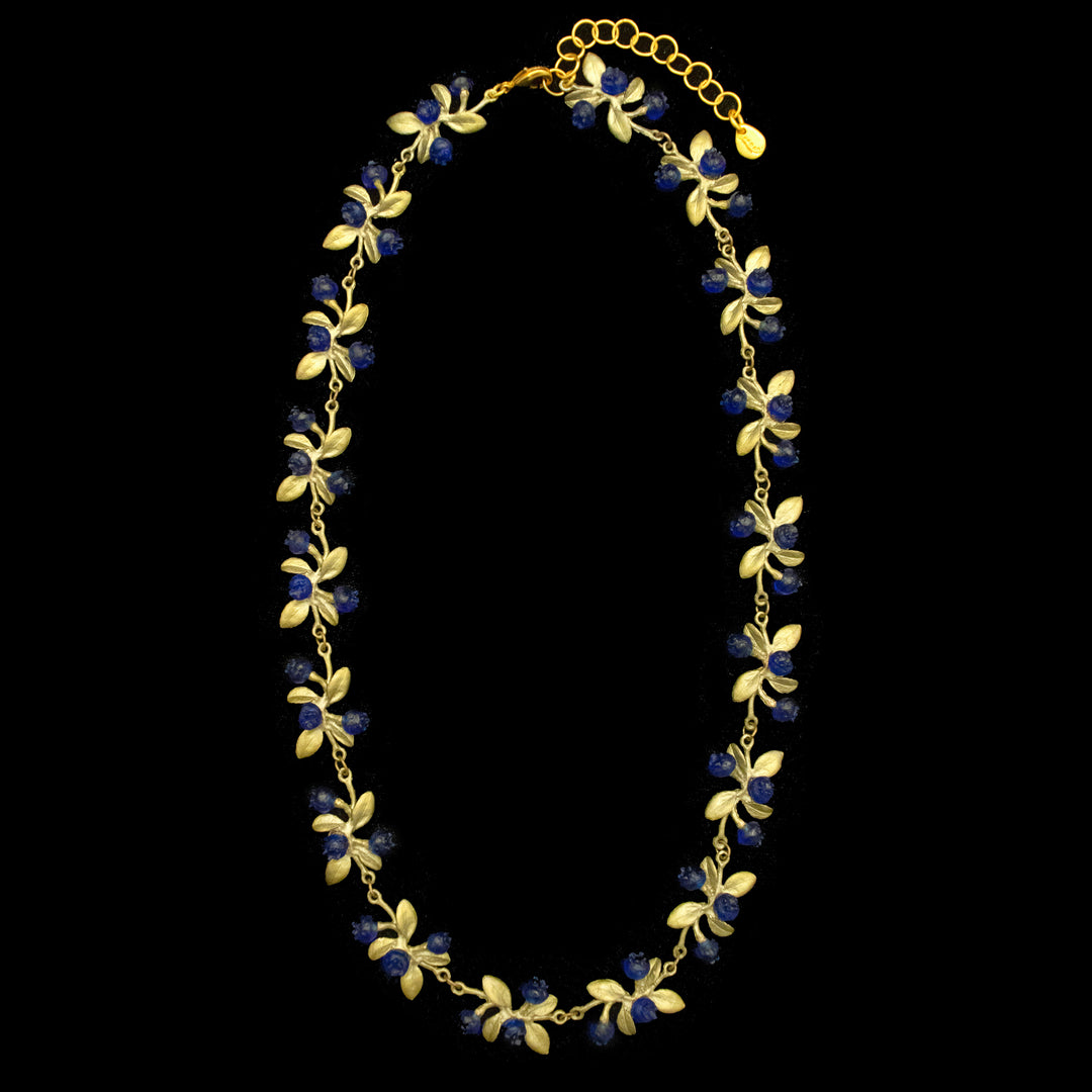 Green necklace with dainty blue berries, connected by green leaves and beautifully displayed on a black background.