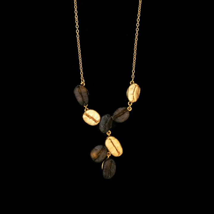 The Roasted Coffee Bean Pendant is a gold-plated bronze Y-shaped necklace, crafted with alternating black and gold oval beans, evoking elegant botanical charm against a striking black background.
