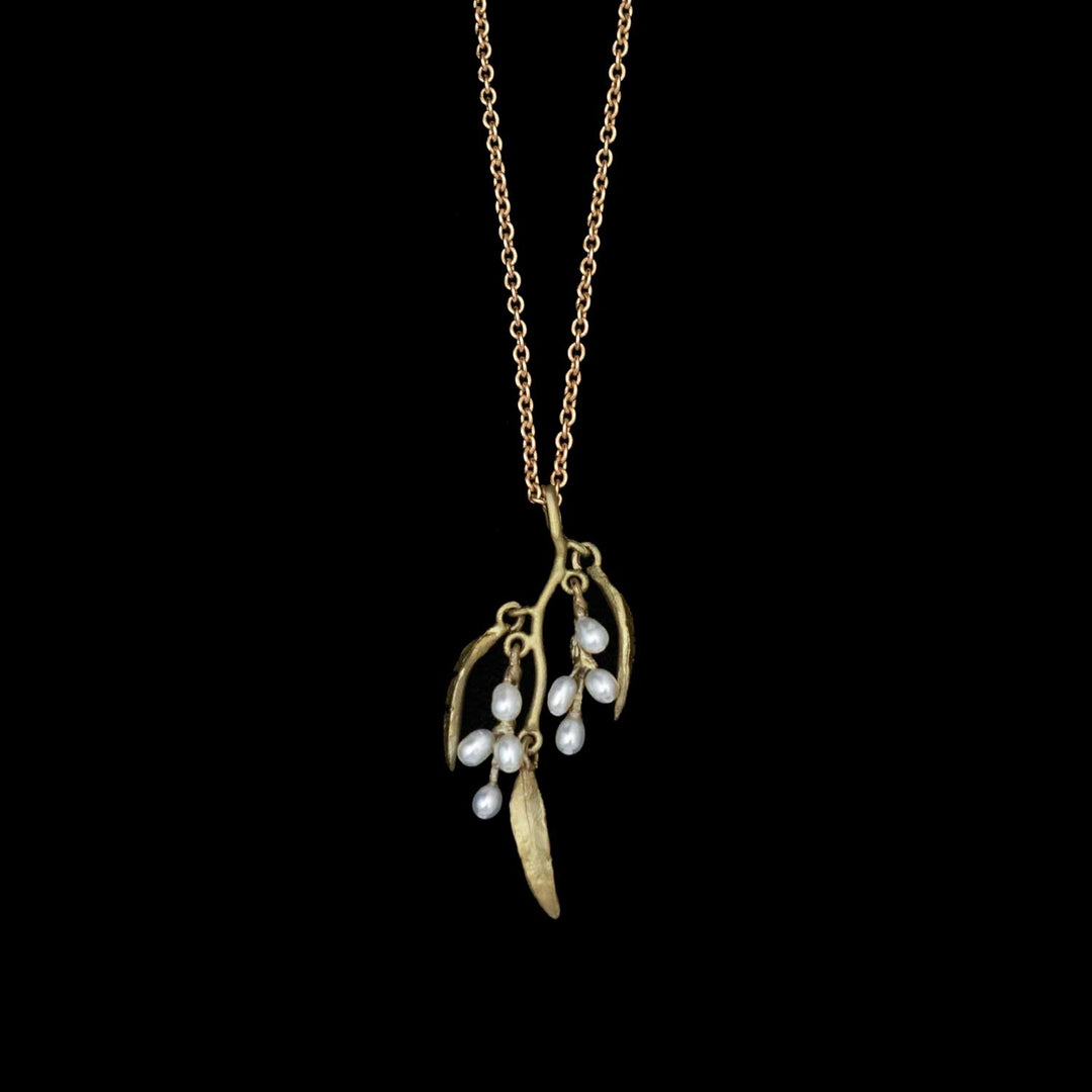 The Weeping Willow Pendant is a gold chain necklace with a hand-patinated bronze willow charm and delicate freshwater seed pearls, displayed against a black background.