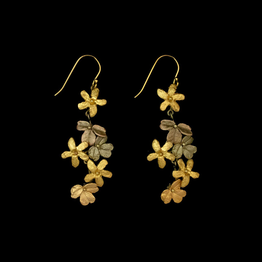 A pair of gold dangle earrings featuring clusters of small, textured flower shapes on a black background—perfect for those who love nature inspired jewelry.