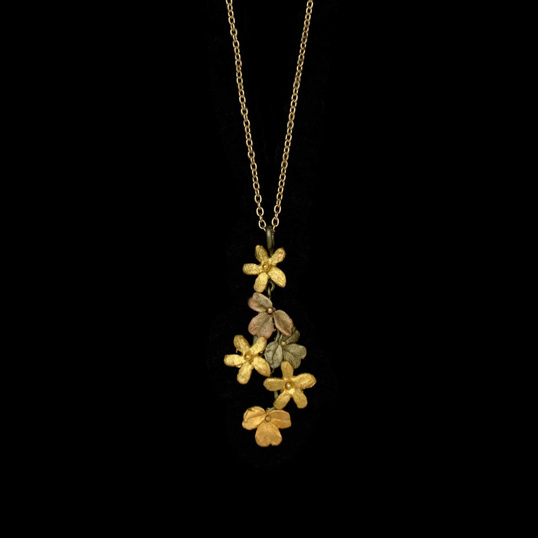A gold chain necklace with a handcrafted bronze pendant featuring multiple metallic flowers in shades of gold, bronze, and copper, displayed against a black background—perfect for lovers of nature-inspired jewelry.
