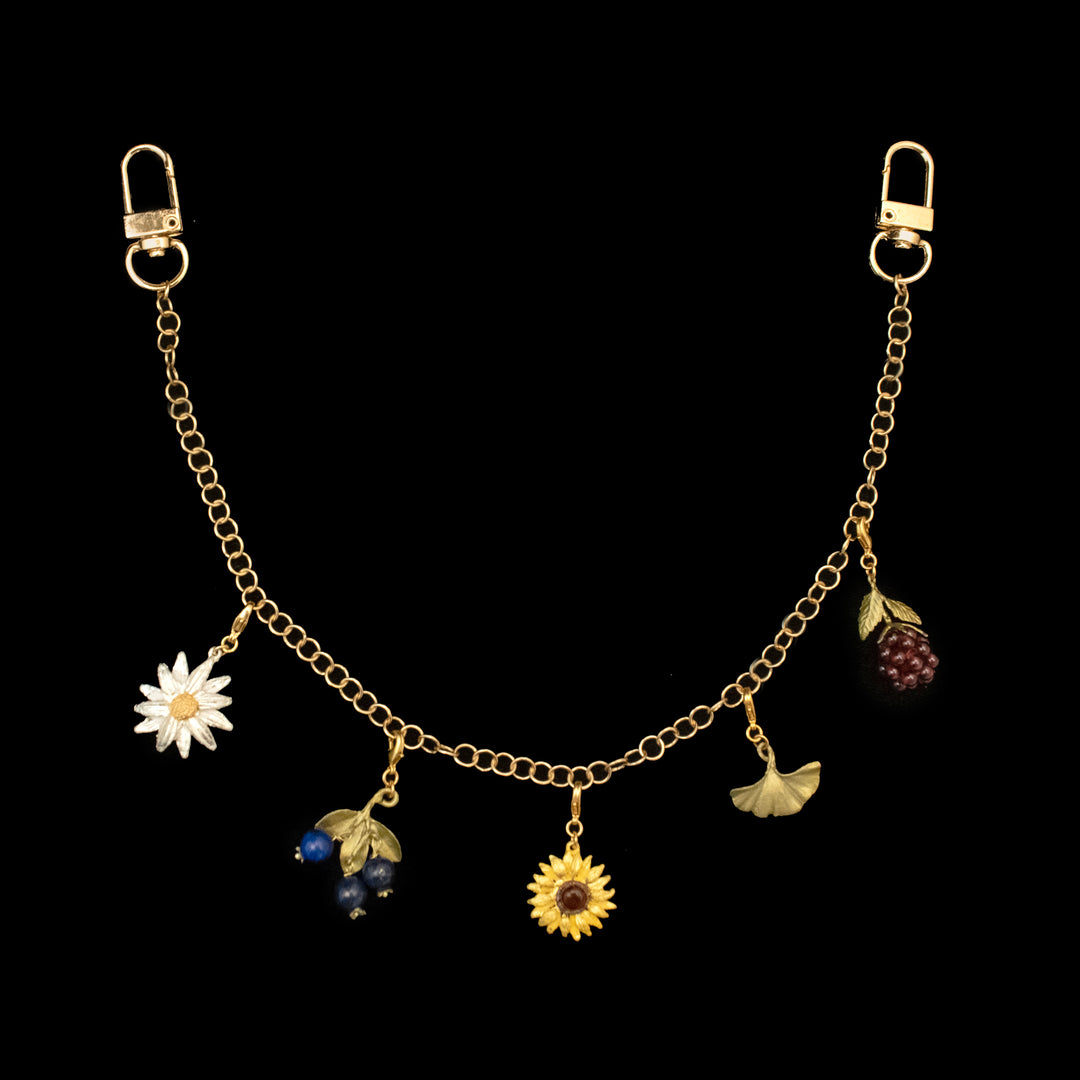 A golden chain with five decorative charms, including a daisy, blue beads with leaves, a sunflower, a ginkgo leaf, and a raspberry, attached with two clasps on each end.