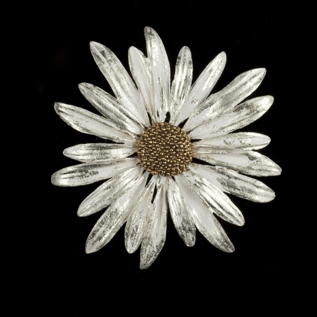 A bronze brooch shaped like a daisy with white gold finish, displayed against a black background.