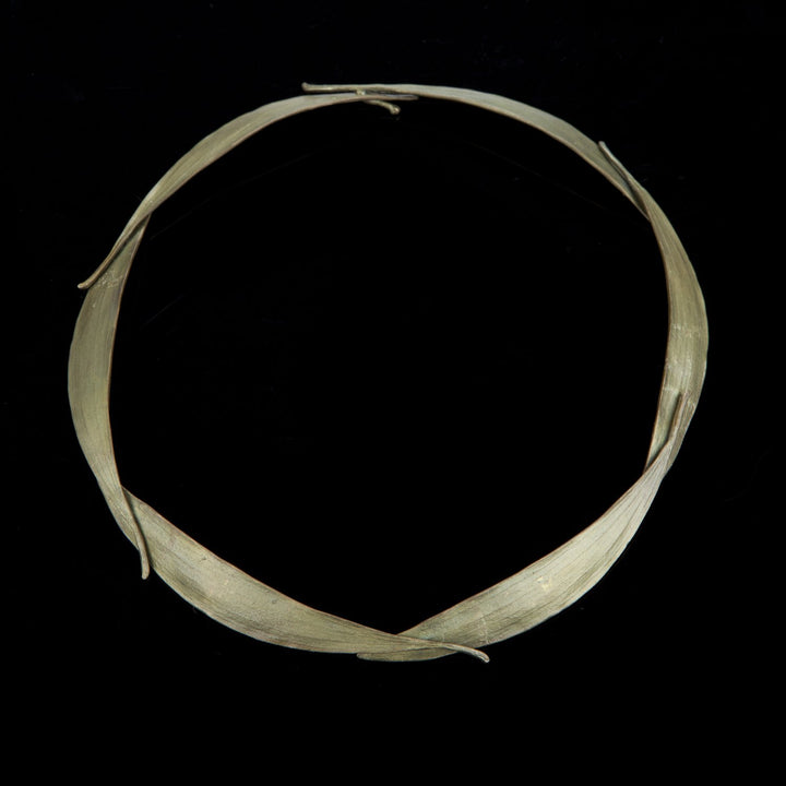 A circular bronze necklace featuring long, slender leaves, displayed against a black background.